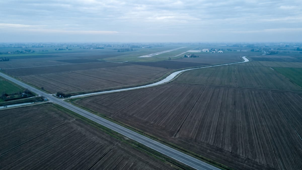 Veduta aerea di campagna con la pista di un aeroporto regionale visibile in lontananza all'orizzonte