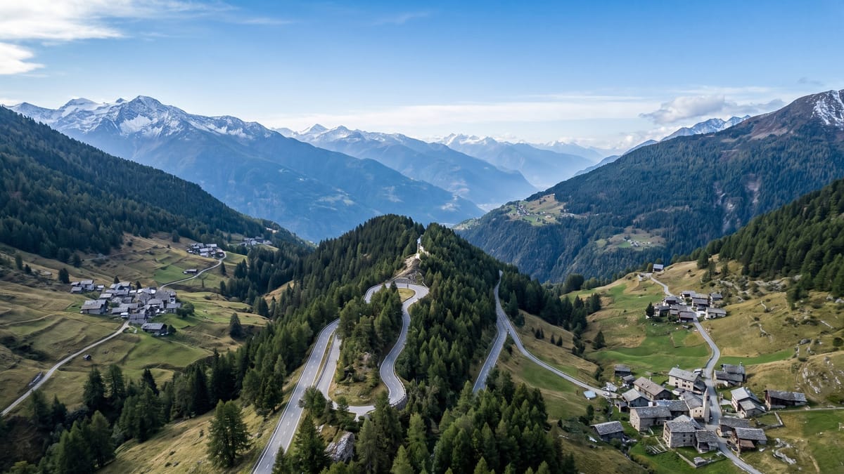Veduta aerea di una valle alpina di confine con due vallate che si incontrano e cime innevate all'orizzonte