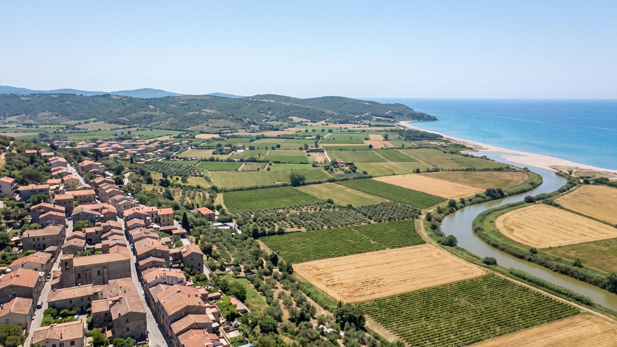 Veduta aerea di una pianura costiera italiana con paese, campi coltivati, fiume e spiaggia nella stessa inquadratura